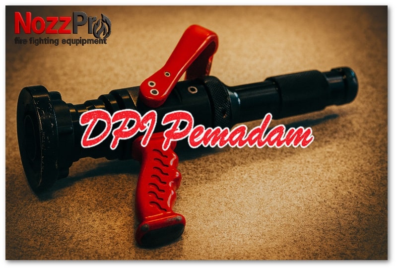 Foto nozzle pemadam kebakaran berwarna hitam dengan pegangan merah, diletakkan di atas permukaan bertekstur dan ditata dalam gaya estetis dengan pencahayaan hangat.